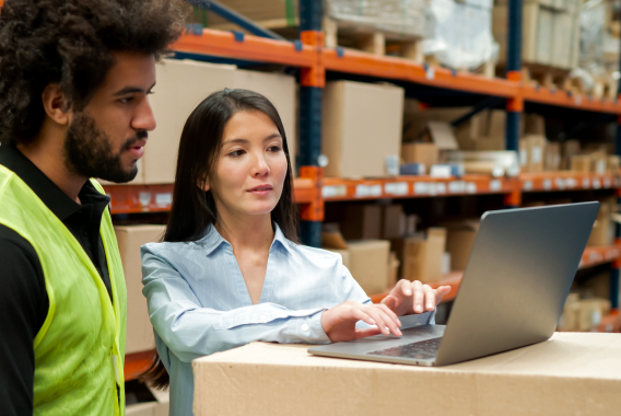 Man and woman looking at a laptop in a warehouse