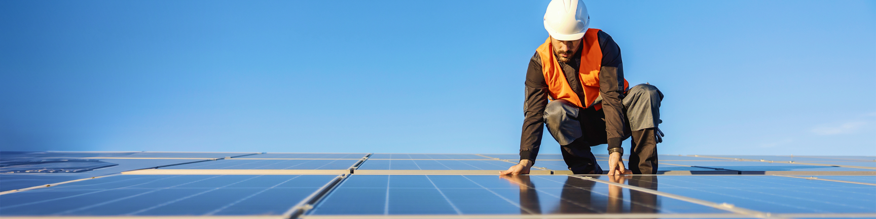 Man with a hardhat on top of solar panels