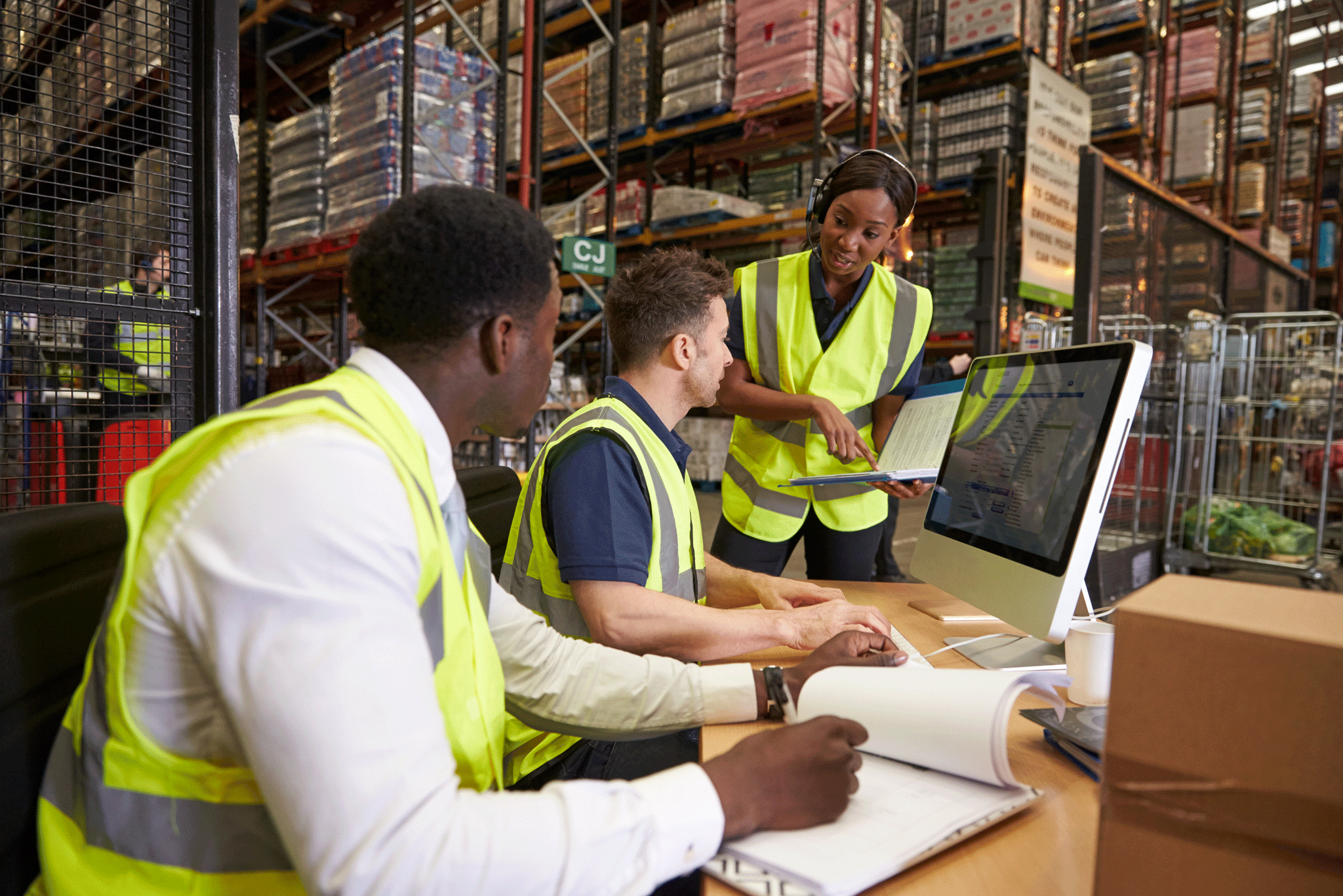 Drie personen in veiligheidsvesten in een warehouse