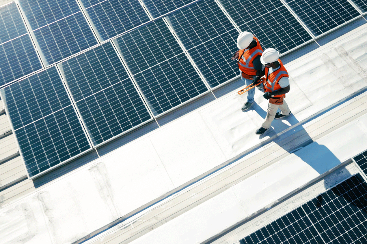 Twee mensen lopen op een dak met zonnepanelen