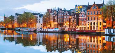 Buildings in Amsterdam at dusk with a canal in the foreground